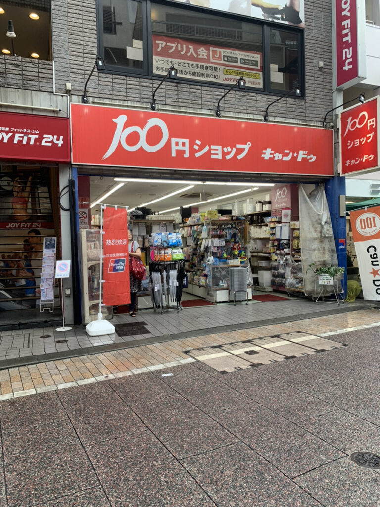 30秒ほど歩くと左手に100円ショップがあります。向かい側が店舗です。