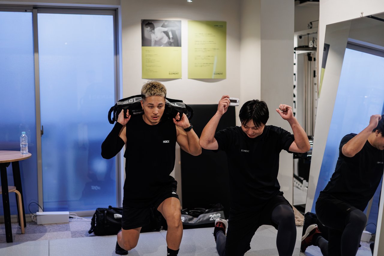 サンドバッグを担いでランジをする男性たち